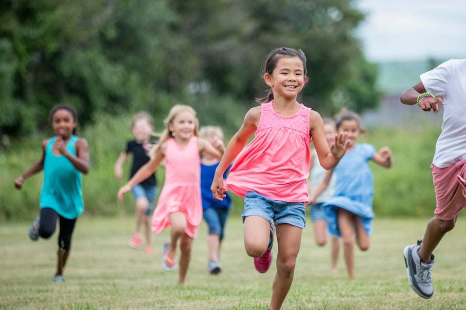 Diverse group of kids playing outside together in the summer.